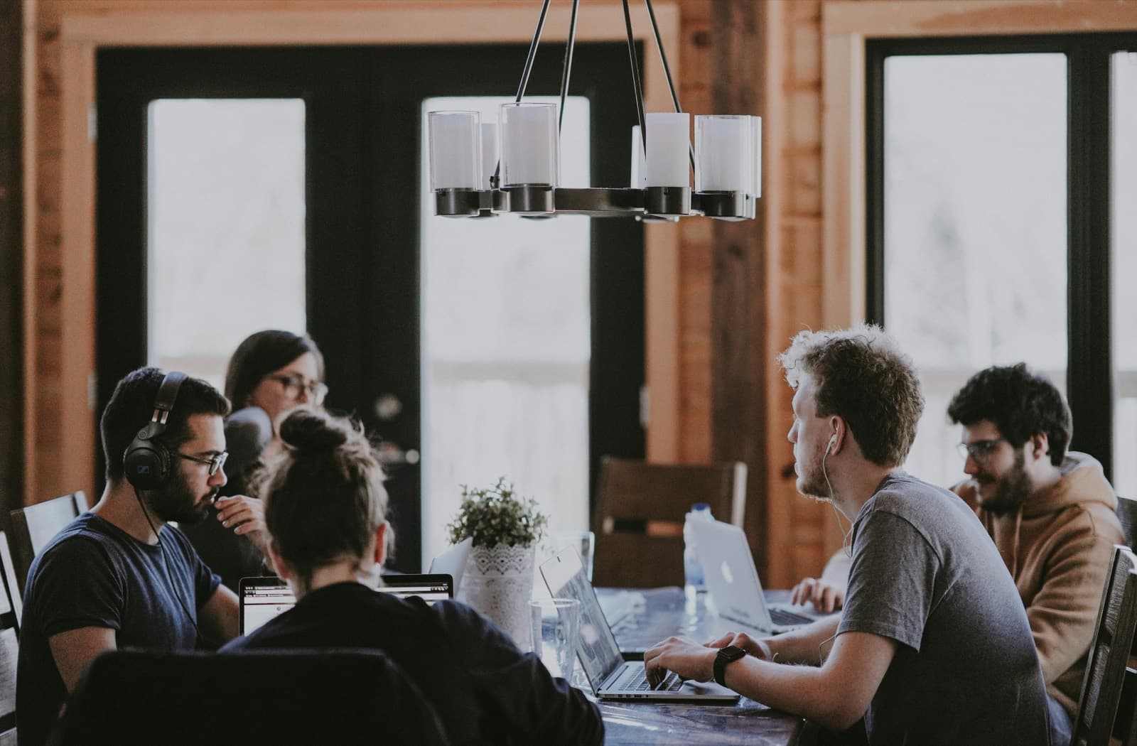 Time reunido em volta de uma mesa longa, com notebooks abertos, trabalhando junto