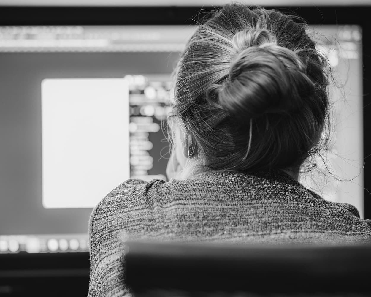 Profissional concentrada diante do monitor, em bloco de trabalho sem interrupção